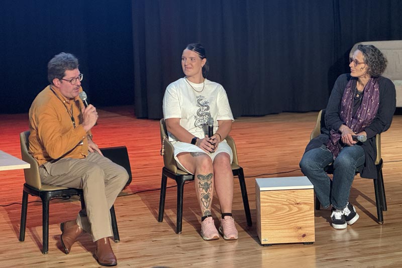 Three people from Toi Ora  seated in chairs in conversation on the stage